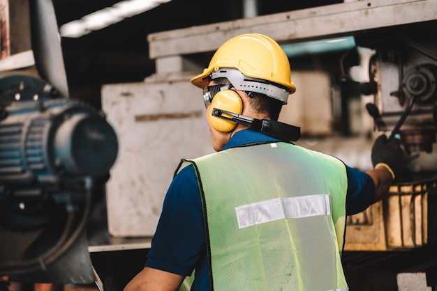 Aziatische werknemer man aan het werk in veiligheid werkkleding met gele helm.