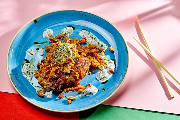 Aziatische wokrijst met kip, pinda's en groenten in een bord op een lichte achtergrond. Selectieve focus, hard licht