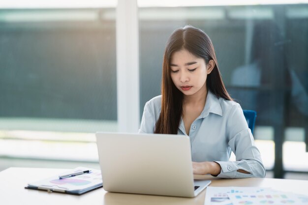 Aziatische zakelijke freelance vrouwenglimlach typen op toetsenbord en werken op laptop op houten tafel thuis Ondernemersvrouw die voor haar bedrijf op kantoor werkt Zakelijk werk op kantoor aan huis