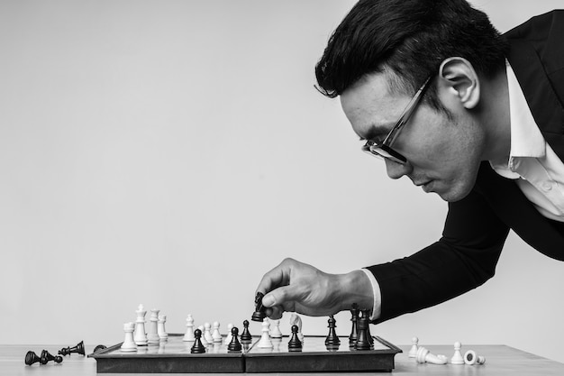 Aziatische zakenman denkt na over zijn volgende zet op het schaakbord