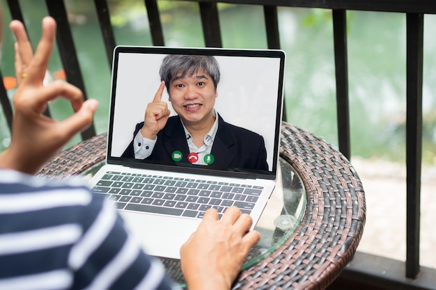 Aziatische zakenman die een videogesprek met klant maakt