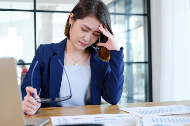 Aziatische zakenman die haar gezicht met beide handen bedekt met de stress van het werk