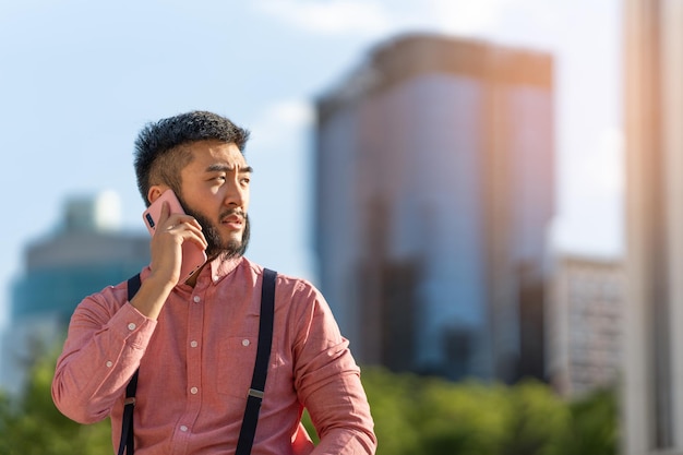 Aziatische zakenman die in de buitenlucht met de mobiele telefoon praat