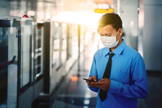 Aziatische zakenman draagt masker en wacht op de trein