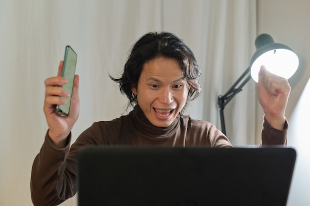 Aziatische zakenman kijkt erg verbaasd naar zijn laptop