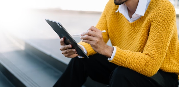 Aziatische zakenman met behulp van een tablet op een bankje in de cityxAxA