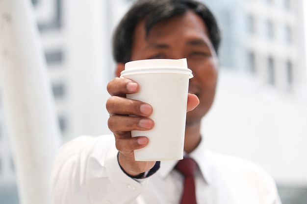 Aziatische zakenman met een koffiekopje bij de hand.