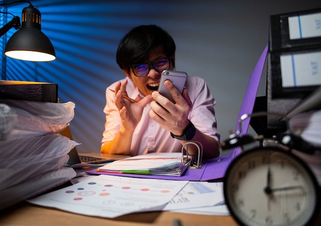 Aziatische zakenman schreeuwt naar mobiele telefoon nadat hij het niet eens kan zijn en stress van zijn werkdeadline 's nachts. ontevreden man. ongelukkig na het werk na verloop van tijd.