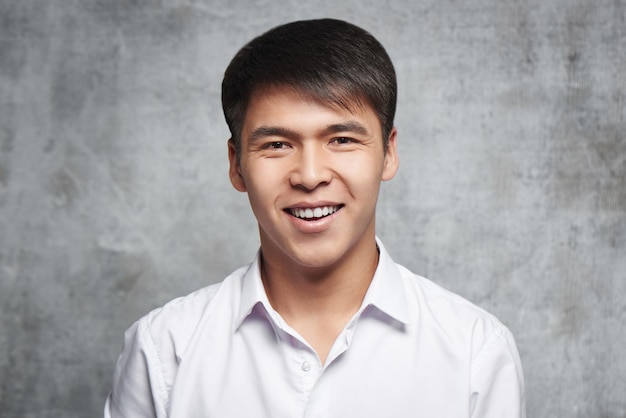 Aziatische zakenman toothy glimlachen. Portret van een jonge aantrekkelijke Kazachse student in een wit overhemd in de studio