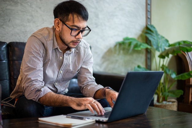 Aziatische zakenman typen op laptop en werken in kantoor aan huis