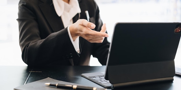 Aziatische zakenvrouw bezig met het analyseren van technische prijsgrafiek en indicator met business team praten via mobiele telefoon account of geld besparen of verzekering concept