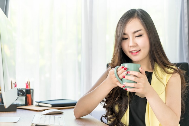Aziatische zakenvrouw blij met koffiekopje