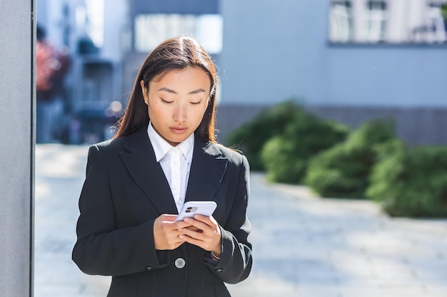 Aziatische zakenvrouw die de telefoon gebruikt, een vrouw in de buurt van het kantoorcentrum, die tijdens een pauze door de stad loopt