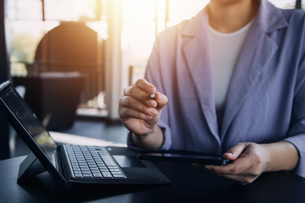 Aziatische zakenvrouw die rekenmachine en laptop gebruikt voor het doen van wiskundefinanciering op een bureau, belastingrapport, boekhoudstatistieken en analytisch onderzoeksconcept