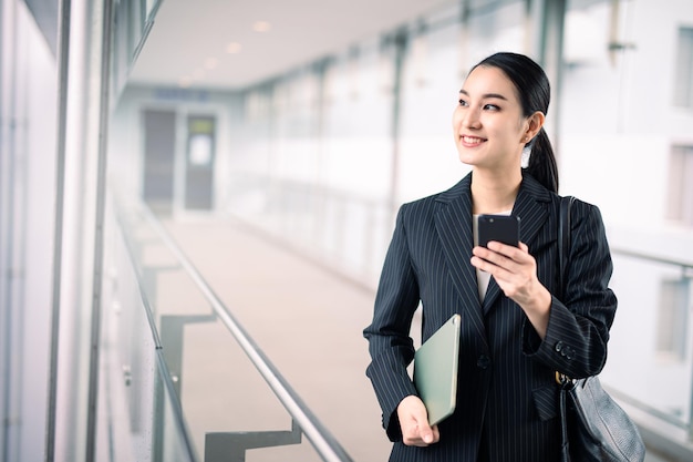 Aziatische zakenvrouw met een tablet en een smartphone op zoek naar een glimlach, slim bedrijfsconcept, slim