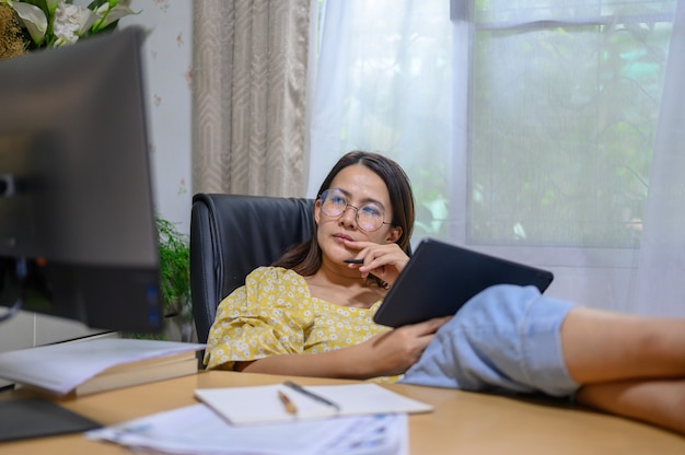 Aziatische zakenvrouw online thuis werken. Thaise vrouwenlevensstijl in woonkamer. Social distancing en het nieuwe normaal.