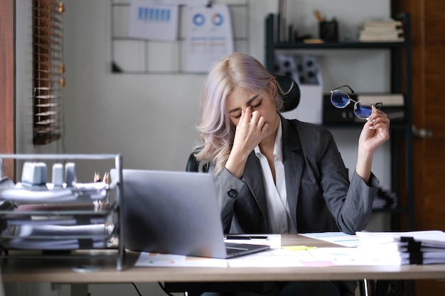 Foto aziatische zakenvrouw verveelt zich stressvol op het werk en denkt veel na over onsuccesvol werk op kantoor