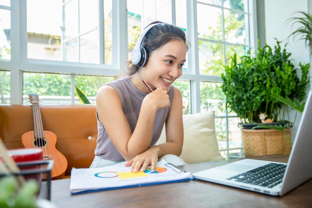 Aziatische zakenvrouwen gebruiken notebooks en dragen een koptelefoon voor onlinevergaderingen en werken vanuit huis.