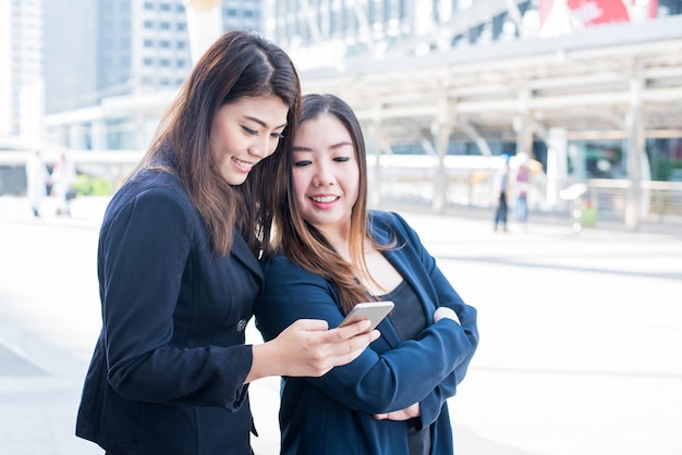 Aziatische zakenvrouwen op mobiele telefoon met vriend na het werk