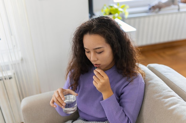 Aziatische zieke zieke vrouw die pijnstillers gebruikt om buikpijn te verlichten, zit 's ochtends op bed zieke vrouw in bed liggend met hoge koorts koude griep en migraine