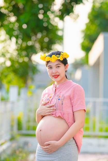 Aziatische zwangere vrouw die een roze robe draagt en gelukkig glimlacht