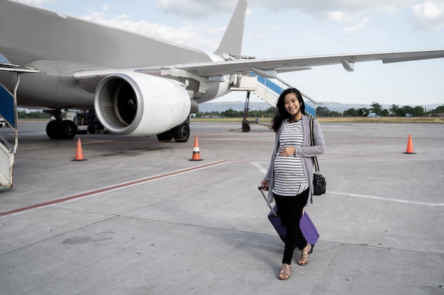 Aziatische zwangere vrouwen trekken koffers tijdens het lopen op de baan