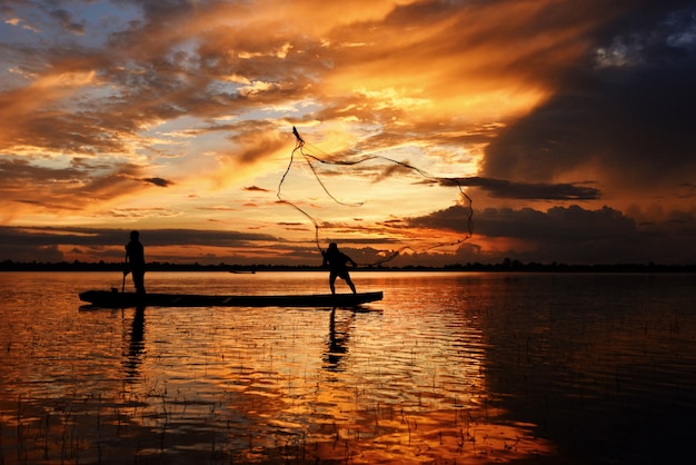 Azië visser netto gebruik op houten boot werpnet zonsondergang of zonsopgang in de Mekong rivier Silhouet vissersboot.