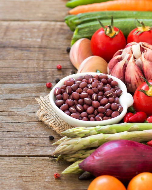 Azuki beans in a bowl and vegetables on wood close up