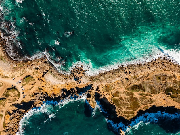 Azure clear water hits the rocky coast of coral beach Aerial top view