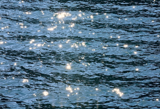 Foto azuurblauw zeewateroppervlak met rimpeling en schitteringen van de zonreflectie