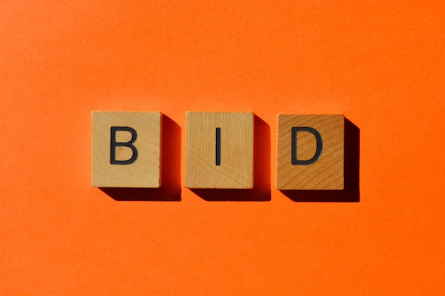 B I D аббревиатура для бизнеса в развитии или разложить его на деревянные буквы алфавита, изолированные на оранжевом фоне