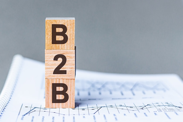 B2b - business to business - acronym on wooden cubes on columns of numbers surface