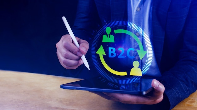 B2C (Business-to-Customer) マーケティング戦略のコンセプト ビジネスマンはビジネスの戦略のコミュニケーション,フィードバック,オンラインマーケティング,電子コマースマーケティングの戦略のために仮想のB2Cアイコンを備えたラップトップを使用します.