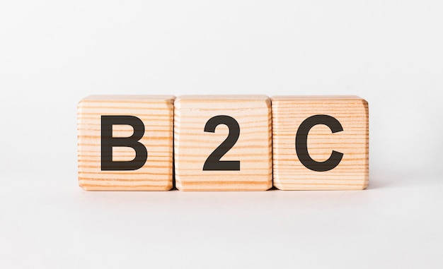 B2C letters of wooden blocks in pillar form on white, copy space