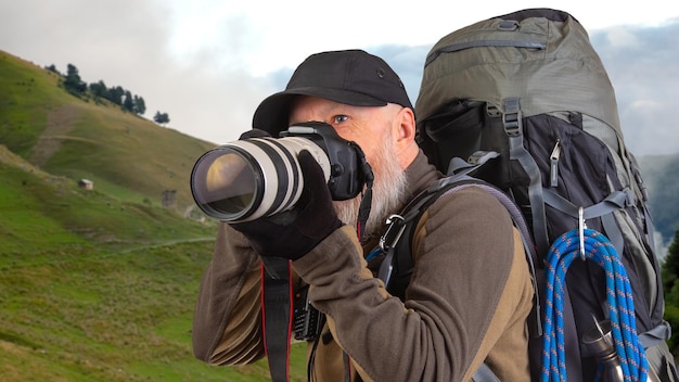 Foto baarde man toeristische fotograaf met een rugzak fotografeert de schoonheid van de natuur