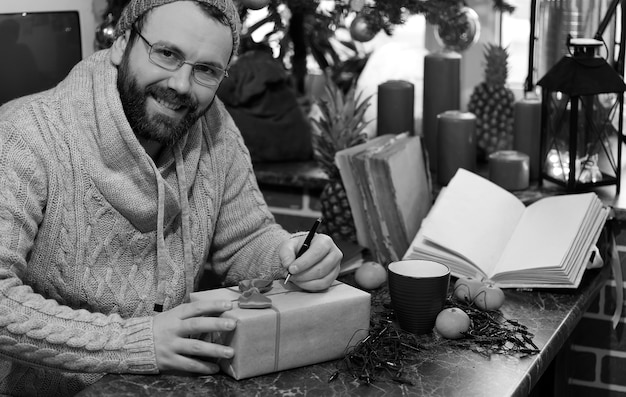 Baardman die kerstcadeaus schrijft op een tafel met oude boeken