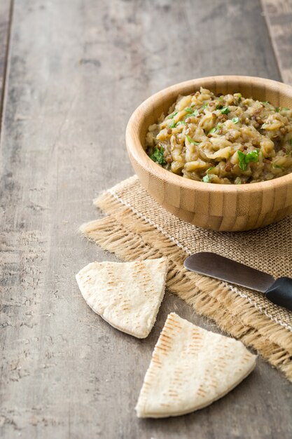 Photo baba ganoush in bowl and pita bread on wooden table