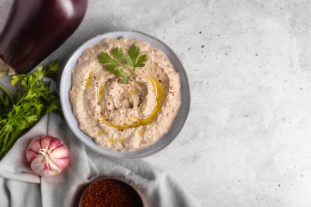 Foto baba ganoush levantijnse keuken voorgerecht gemaakt van gebakken aubergine en sesampasta met kruiden en olijfolie op een betonnen ondergrond. ruimte kopiëren