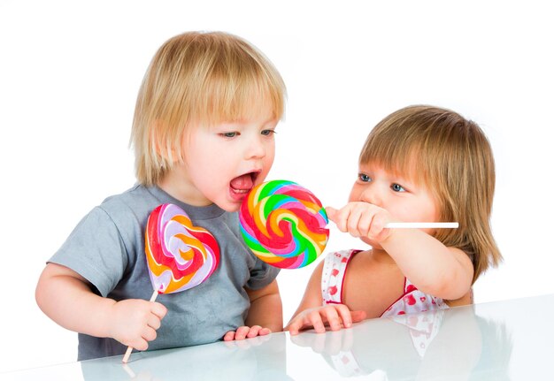 Babies eating a sticky lollipop on white background