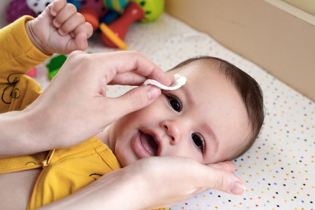 babies and newborn hygiene and healthcare Closeup of cleaning and washing baby face with soft cottong pad