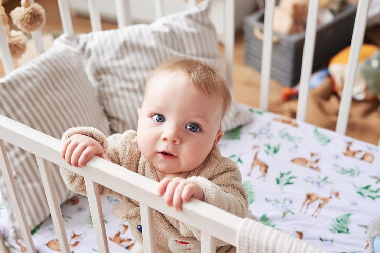 Baby 6 months standing in crib in children's room. Happy motherhood and fatherhood. Maternity hospital and clinic. Father and mother day. Early childhood development, nursery