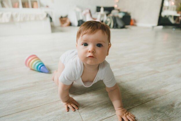 Baby 69 months old playing with a colorful rainbow toy pyramid sitting in a white sunny bedroom Toys for small children Children's interior A child with an educational toy