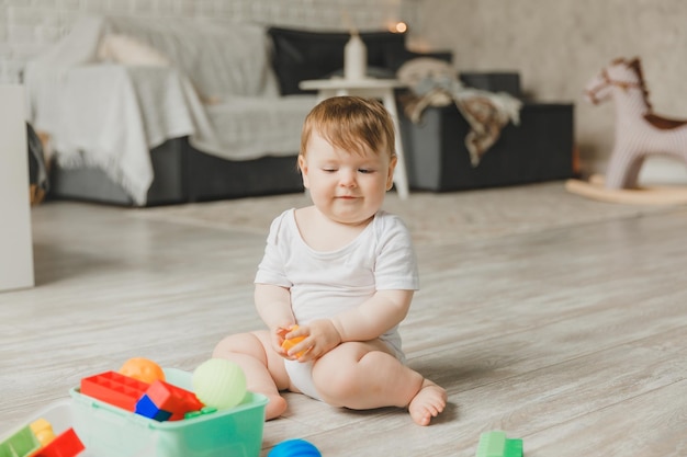 Baby 69 months old playing with a colorful rainbow toy pyramid sitting in a white sunny bedroom Toys for small children Children's interior A child with an educational toy