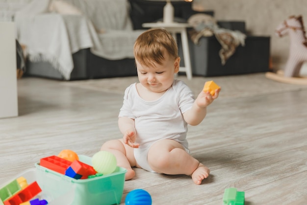 Baby 69 months old playing with a colorful rainbow toy pyramid sitting in a white sunny bedroom Toys for small children Children's interior A child with an educational toy