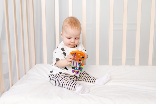 Baby 8 months playing in the crib, early development of children up to a year, a place for text