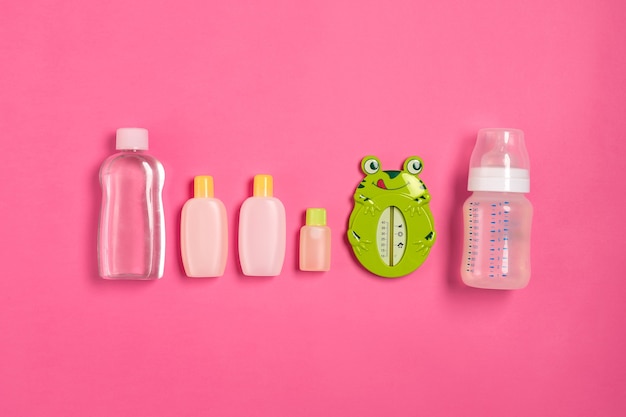 Baby accessories for bath with frog on pink background. Top view. Copy space. Still life. Flat lay