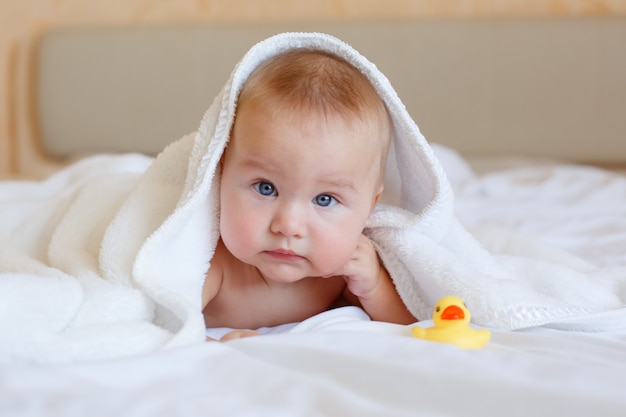 Baby after bathing wrapped in a towel lying on the bed