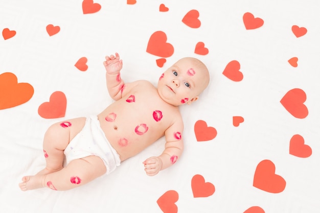 Photo baby among hearts and with kisses from red lipstick, the concept of love and valentine's day