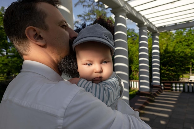 Bambino tra le braccia di papà in una giornata di sole su uno sfondo chiaro