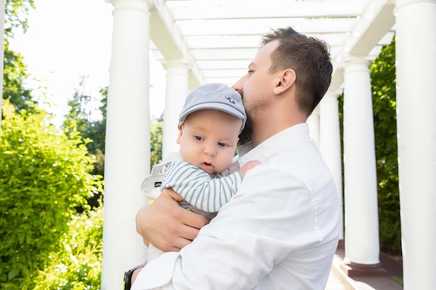 Baby in the arms of dad on a sunny day on a light background